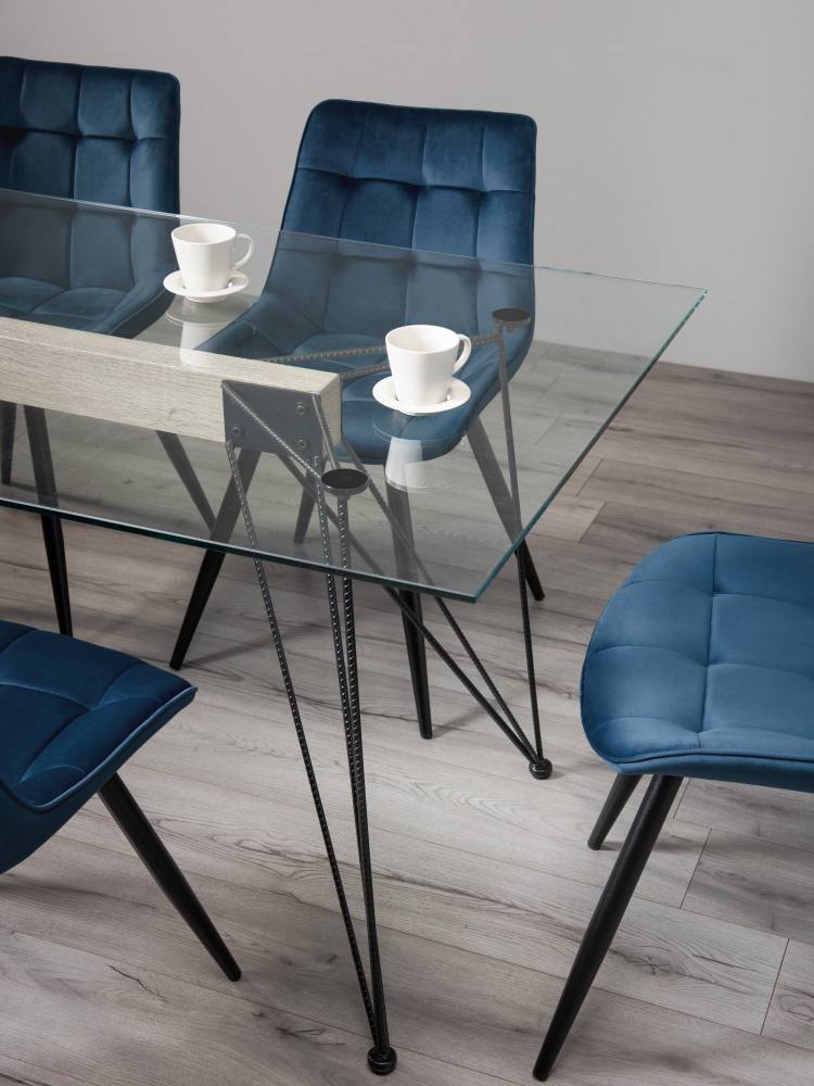 Close Up of the Bentley Designs Miro Clear Tempered Glass 6 Seater Dining Table & 6 Seurat Blue Velvet Fabric Chairs with Sand Black Powder Coated Legs