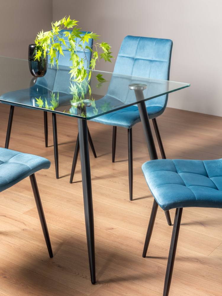 Close Up of the Bentley Designs Martini Clear Tempered Glass 6 Seater Dining Table & 4 Mondrian Petrol Blue Velvet Fabric Chairs with Sand Black Powder Coated Legs