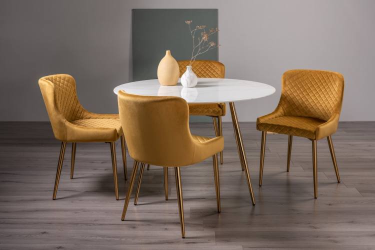 The Bentley Designs Francesca White Marble Effect Tempered Glass 4 Seater Dining Table with 4 Cezanne Mustard Velvet Fabric Chairs with Matt Gold Plated Legs