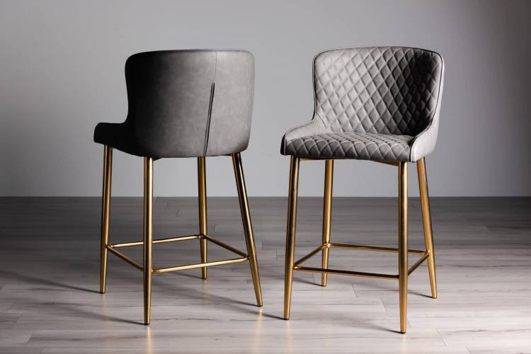 The Bentley Designs Cezanne Dark Grey Faux Leather Bar Stools with Matt Gold Plated Legs on Display 