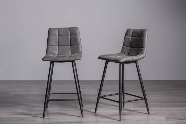 The Bentley Designs Mondrian Dark Grey Faux Leather Bar Stools with Sand Black Powder Coated Legs (Pair)